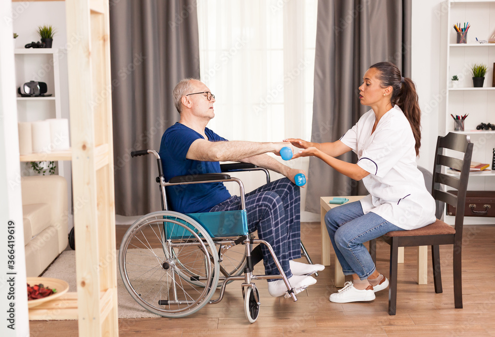 Fototapeta premium Disabled old man during physiotherapy talking with doctor about his pain. Disabled handicapped old person with social worker in recovery support therapy physiotherapy healthcare system nursing