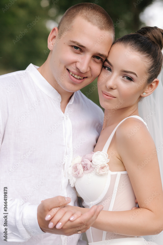 Young and beautiful bride with handsome groom hug each other kiss and smile. Portrait of happy wedding couple Young and beautiful bride with handsome groom hug each other kiss and smile. Portrait of happy wedding couple