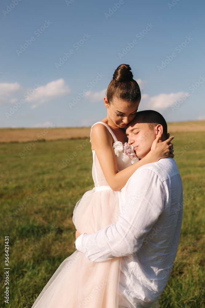 Newlyweds walking in field. Groom hug bride after wedding ceremony Newlyweds walking in field. Groom hug bride after wedding ceremony