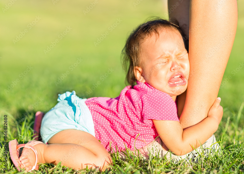 Foto de Crying child attached onto parents legs throwing tantrums at