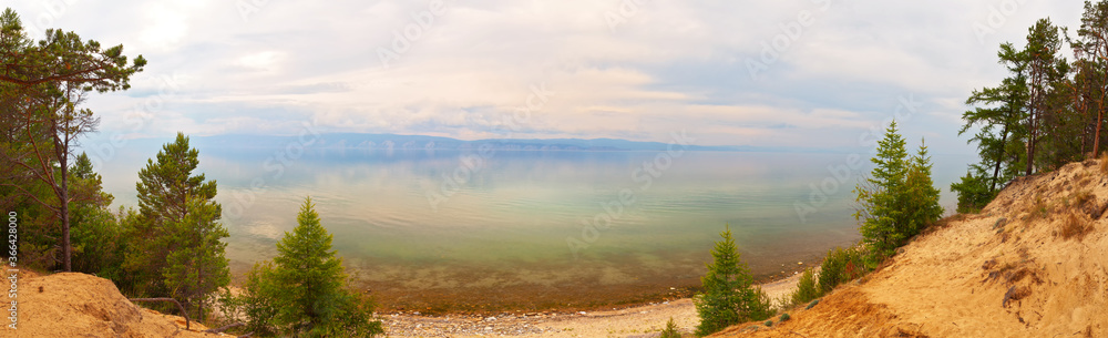 Baikal Lake. Panoramic view from Olkhon Island to the Small Sea Strait on a quiet, foggy summer day. Coastal forest on sandy hills in the Sasa terrain. Beautiful landscape