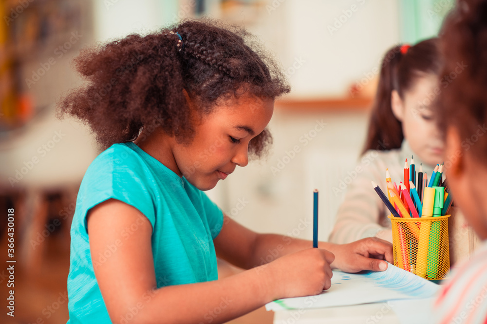 Girl drawing with a blue pencil during the art class Girl drawing with a blue pencil during the art class