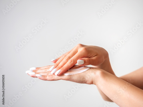 female hands apply cream. Close-up. Light background. Body care