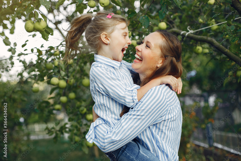 Fashionable mother with daughter. Family in a spring park. Woman in a blue shirt Fashionable mother with daughter. Family in a spring park. Woman in a blue shirt