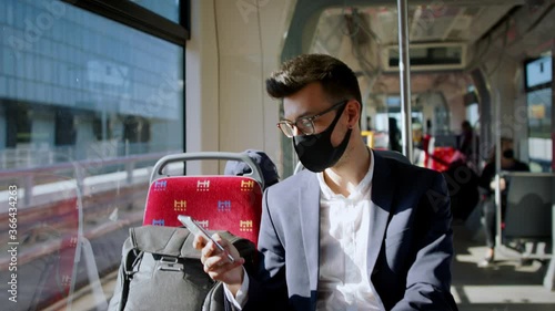 Portrait of young businessman with face mask sitting in public transport, travelling to work. photo