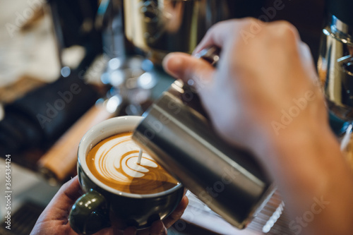 barista making latte art  shot focus in cup of milk and coffee  vintage filter image