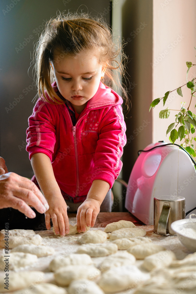 Fototapeta premium Grandmother and granddaughter sculpt dumplings with meat filling.