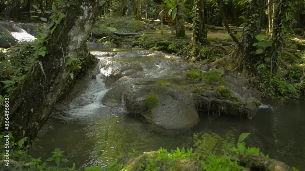 Reveal wonderful scenery of water stream flowing from cascade over the rocks through green plant under sunlight in fertile forest. Sa Nang Manora forest park. Phang Nga Province. Thailand. Reveal wonderful scenery of water stream flowing from cascade over the rocks through green plant under sunlight in fertile forest. Sa Nang Manora forest park. Phang Nga Province. Thailand.