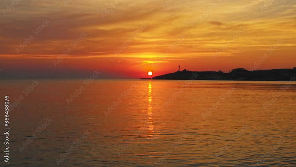 A golden idyllic sunset as the sun sets into the waters of the gentle ocean surf A golden idyllic sunset as the sun sets into the waters of the gentle ocean surf