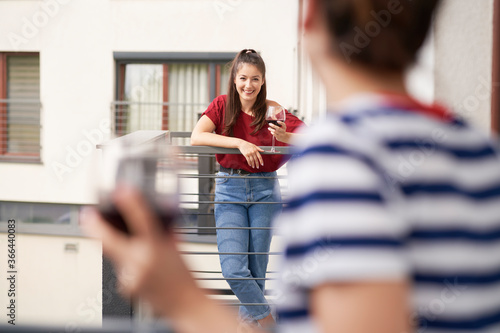 Women chatting while standing on their balconies photo