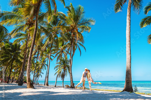 Kissing couple on tropical beach with palm trees