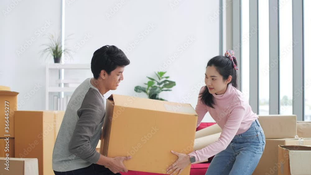 Asian couple carrying big cardboard box at new home.Moving house. relocation and welcome. Happy Couple Moves in New Home. Asian couple carrying big cardboard box at new home.Moving house. relocation and welcome. Happy Couple Moves in New Home.