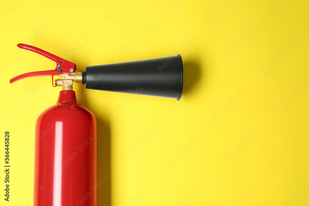 Fire extinguisher on yellow background, top view. Space for text