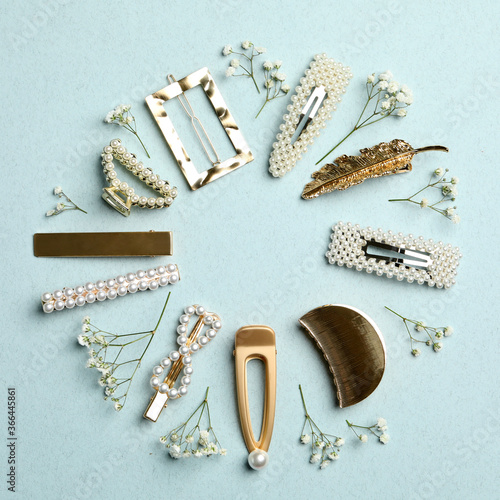 Frame of stylish hair clips and flowers on light background, flat lay