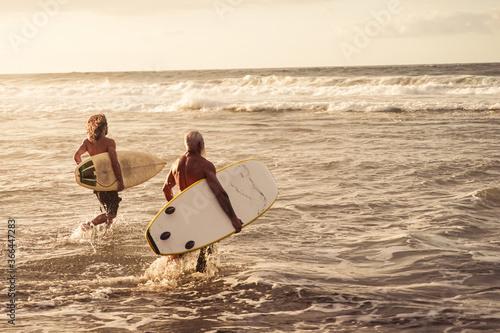 Photography Friends going to surf on the beach at sunset