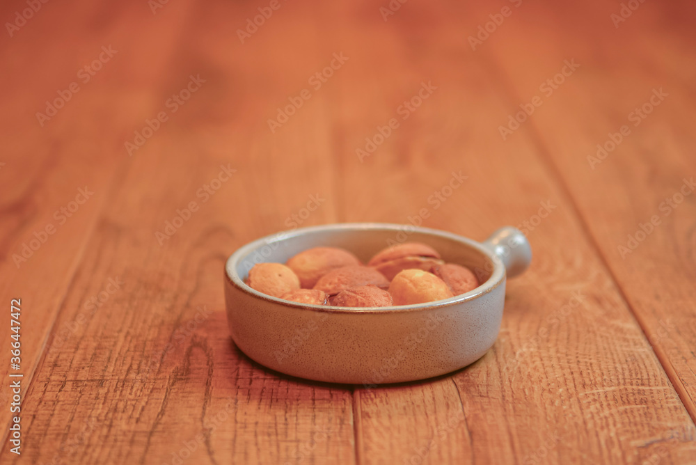 Cookies called nuts with condensed milk served in a white bowl on a wooden table over blurred restaurant background.