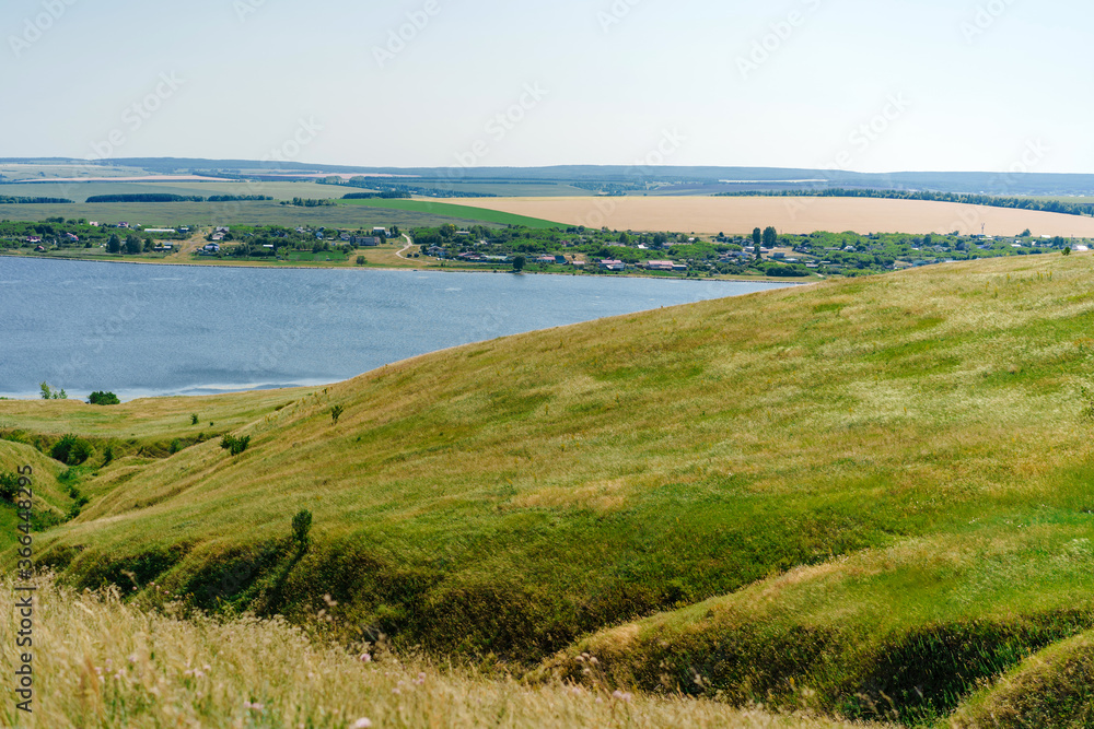 Large panoramic view of the landscape of wheat fields, ears and yellow-green hills, mountain view with lakes Large panoramic view of the landscape of wheat fields, ears and yellow-green hills, mountain view with lakes