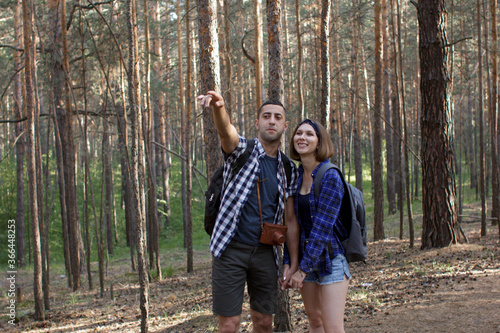 young couple with backpacks hiking in a coniferous forest
