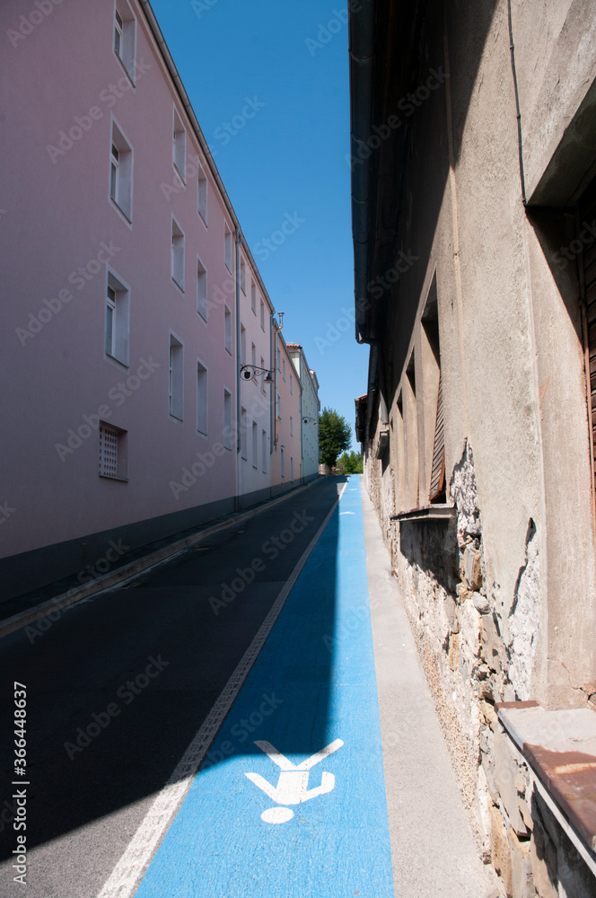 Narrow street with blue pedestrian path in Izola city, Slovenia