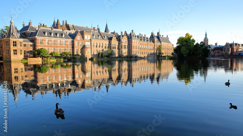 Reflections of the Binnenhof  13 century gothic castle  on the Hofvijver lake  with the clock tower of Grote of Sint Jacobskerk on the right  The Hague  Netherlands