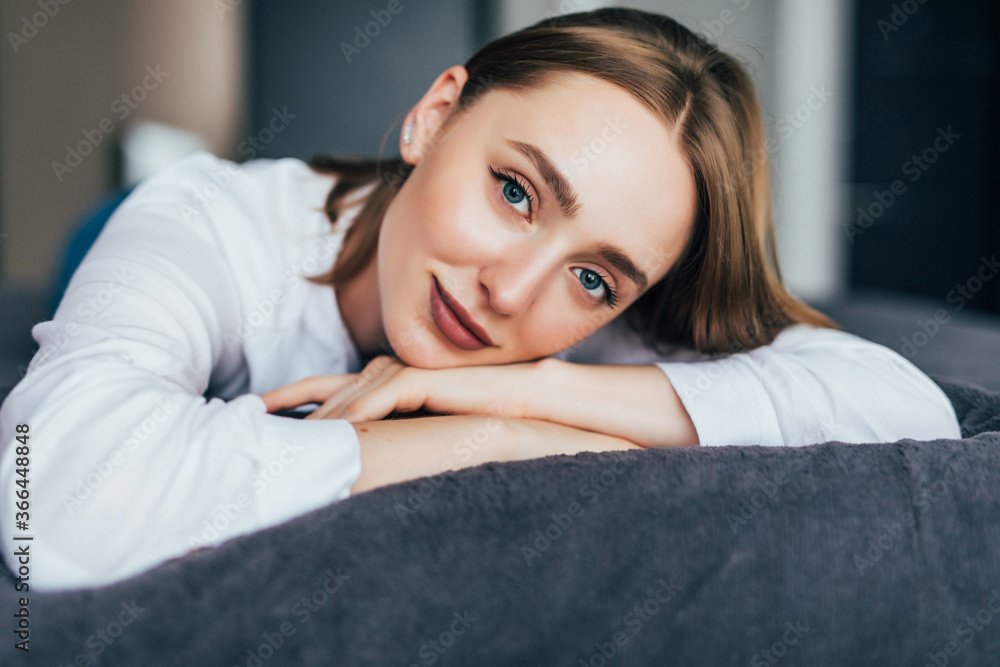 Pure beauty. Beautiful young woman adjusting her hair and looking at camera while lying on the bed at home Pure beauty. Beautiful young woman adjusting her hair and looking at camera while lying on the bed at home