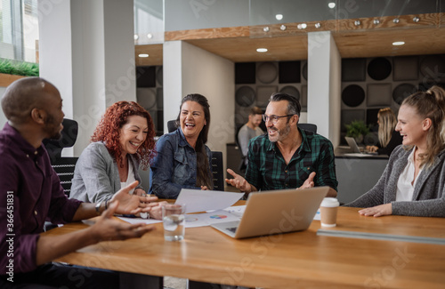 Smiling group of businesspeople talking together during an office meeting