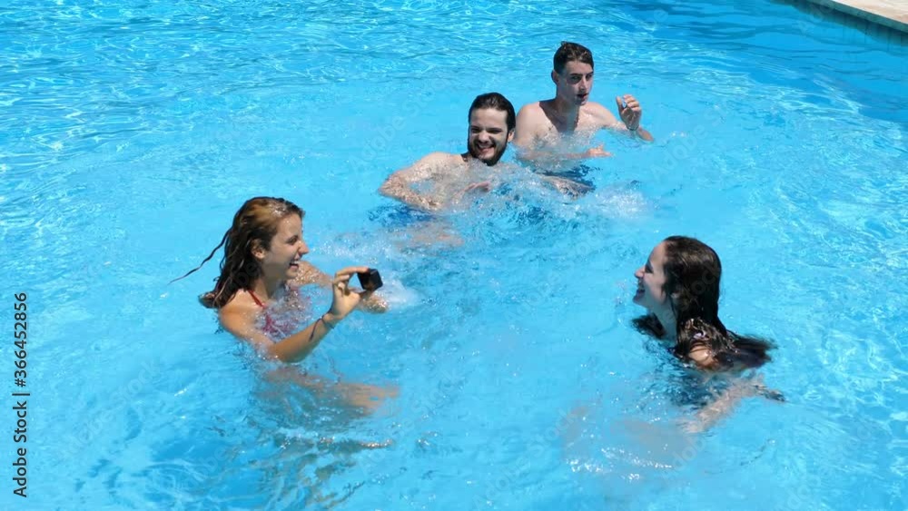 happy young friends playing and splashing in the pool.Summertime, joy, happiness happy young friends playing and splashing in the pool.Summertime, joy, happiness