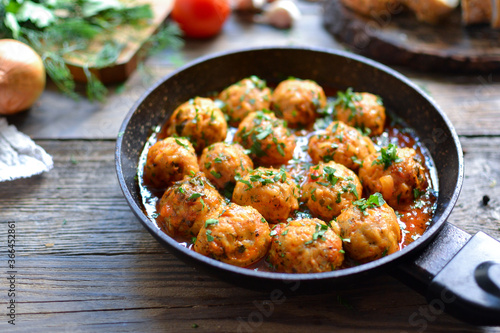 Chicken meatballs in tomato sauce in a pan. Recipe and Step by Step Cooking. Wooden background.