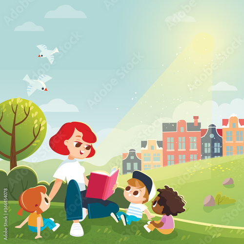 Mother reading a book for kids sitting on medow, lawn outskirts of the city. Babysitter teaches child to read. Early education.