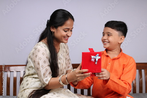 Cute Indian boy and girl celebrating festival and sharing gifts. Its a front facing photo in which brother sister duo spending family time and enjoying fun moments.