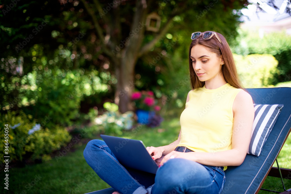 Young woman using laptop in the garden while working from home Young woman using laptop in the garden while working from home