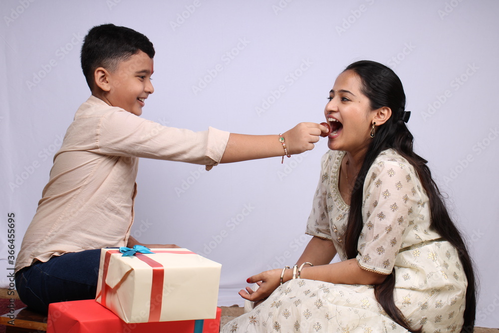 Beautiful Indian girl and cute boy celebrating festival feeding sweets to each other. its a front facing photo in which brother sister duo enjoying family time and fun moments. Beautiful Indian girl and cute boy celebrating festival feeding sweets to each other. its a front facing photo in which brother sister duo enjoying family time and fun moments.