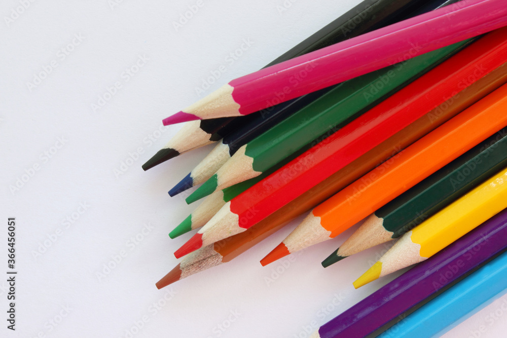 Fototapeta premium Colored pencils white background. Lots of different colored pencils. Colored pencil. Pencils are sharp. Pencils lie on the left. Close-up. Copy space. Background. Flat lay.