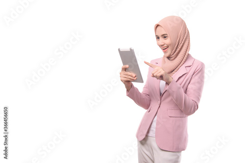 Smiling young muslim woman in hijab pink clothes hold ipad, isolated on white wall background, studio portrait. People religious lifestyle concept. Mock up copy space
