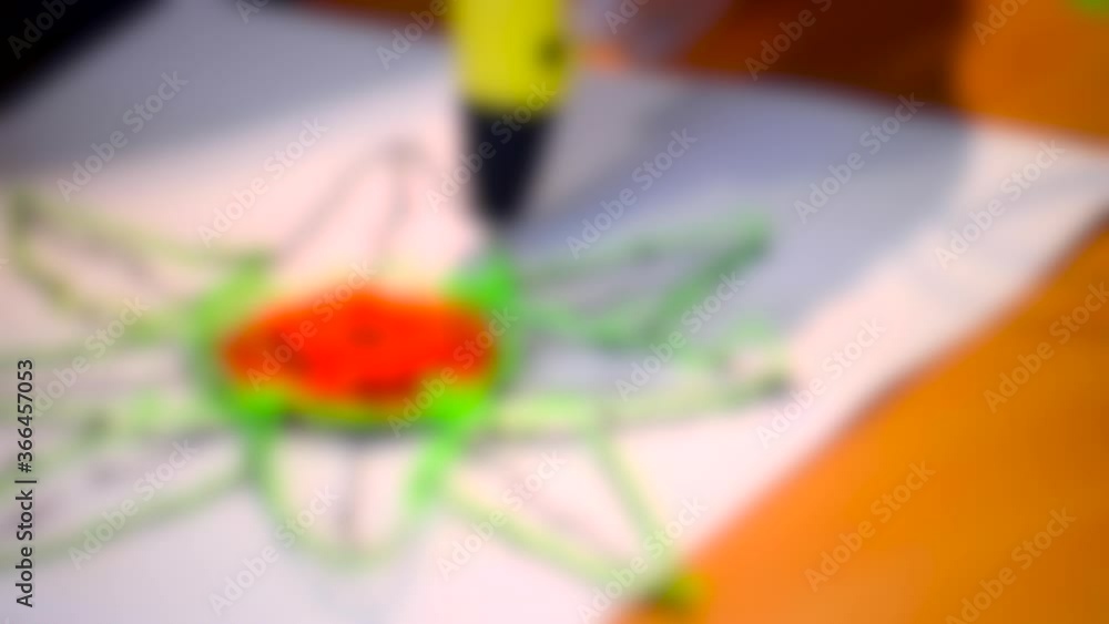 Blurred background. The man paints a flower 3d-pen close-up Blurred background. The man paints a flower 3d-pen close-up