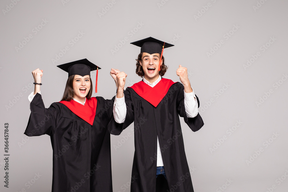 Young Couple in graduation gowns holding diplomas and celebrate isolated on white background Young Couple in graduation gowns holding diplomas and celebrate isolated on white background
