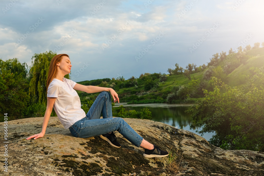 Relaxation, meditation, Digital detox, wellbeing, mental health concept. Red-haired woman meditates and relaxes in nature outdoor rocks at sunset.