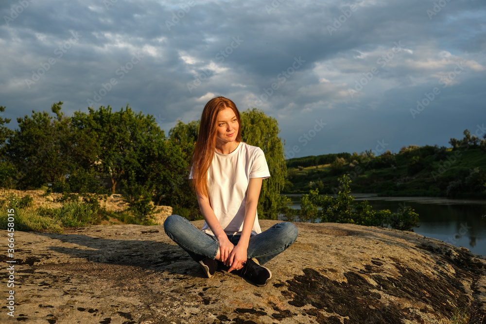 Relaxation, meditation, Digital detox, wellbeing, mental health concept. Red-haired woman meditates and relaxes in nature outdoor rocks at sunset.