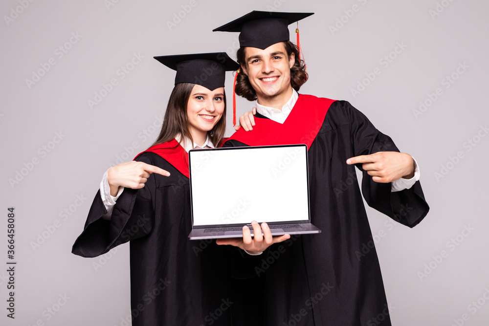 Young graduation couple holding laptop on white background Young graduation couple holding laptop on white background