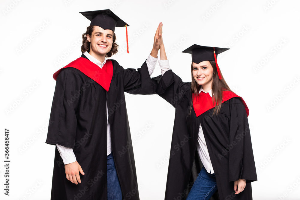 Two happy college graduates giving high five smiling after receiving diplomas over white background. Two happy college graduates giving high five smiling after receiving diplomas over white background.