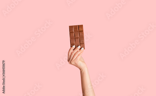 Bild auf Leinwand Millennial woman holding bar of organic chocolate over pink background, close up