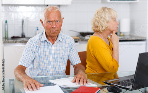 Unhappy mature couple with documents having conflict in home interior