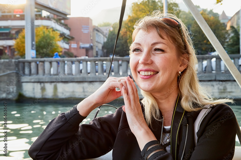 Fototapeta premium Portrait of young caucasian girl relaxing near water of river and promenade background in a sunny summer, spring or autumn day