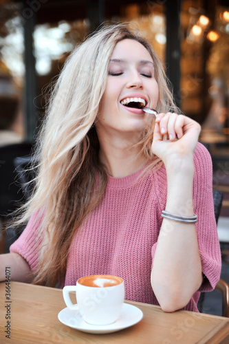 Beautiful woman in sweater drinks coffee outdoors 