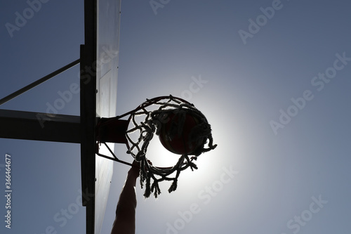 A guy throws a basketball hoop on a street basketball court. Shooting in contoured light from the sun