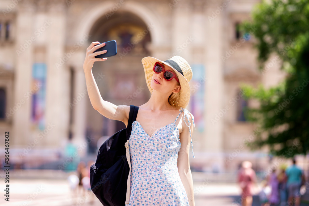 Happy young female tourist making selfie in the city