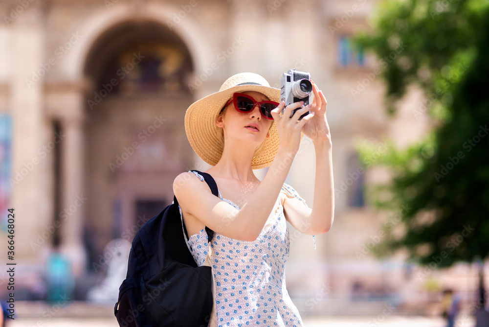 Shot of young woman taking pictures with vintage camera while sightseeing in the city