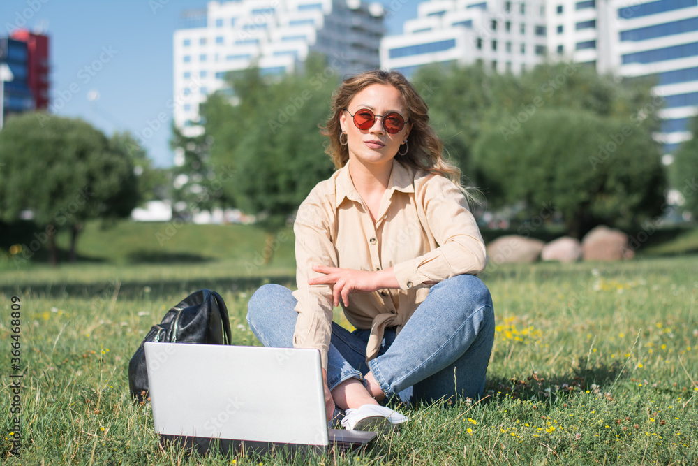 girl student sitting on the lawn on campus and working on a laptop girl student sitting on the lawn on campus and working on a laptop