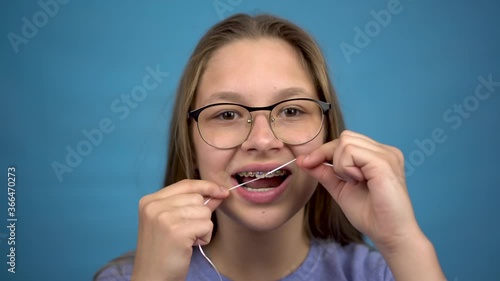 Wallpaper Mural Girl with braces brushing your teeth with dental floss. A girl with colored braces on her teeth keeps her teeth clean. Torontodigital.ca