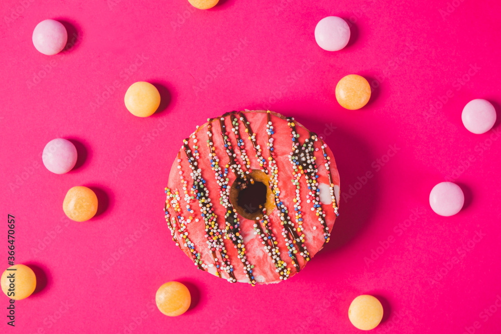 close up of a pink donut on a pink background with colorful candies close up of a pink donut on a pink background with colorful candies
